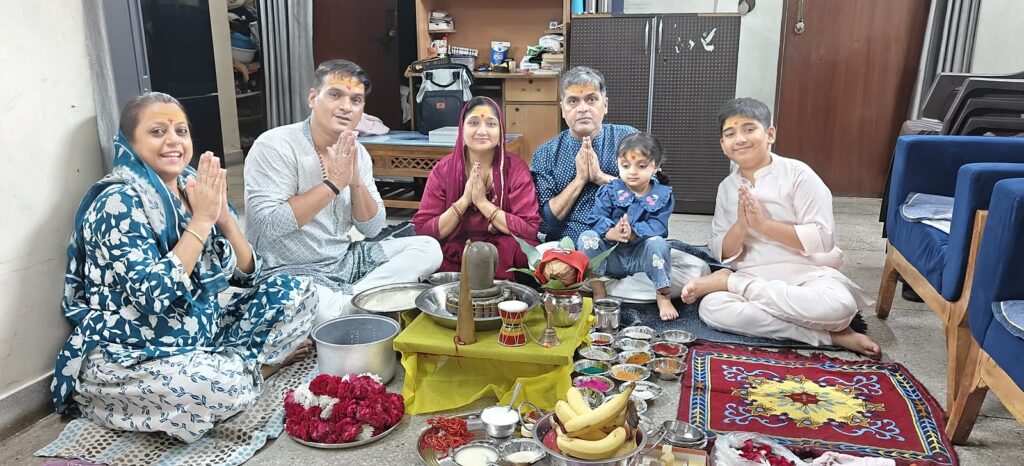 A family seated with folded hands around the Shivling during a Rudrabhishek puja at their home in Delhi NCR