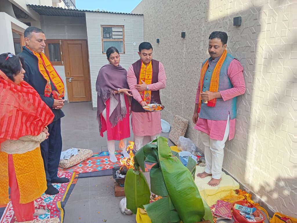 Family gathered around the havan with the pandit during a Griha Pravesh at their new home
