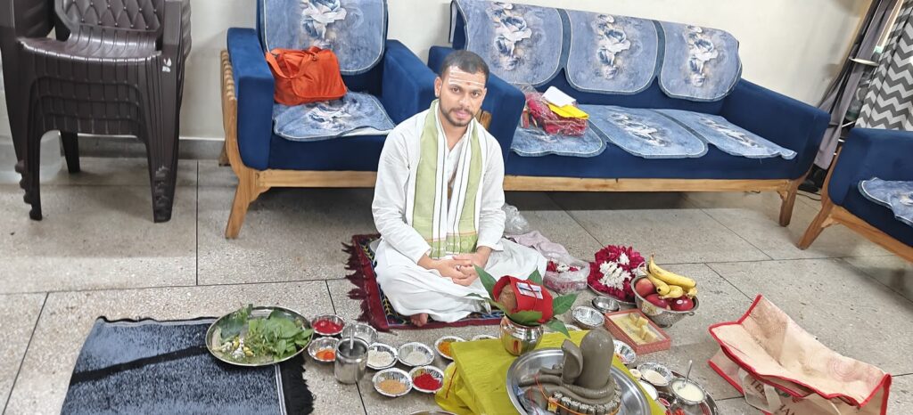Pandit seated with the Shivling and puja thalis during a Rudrabhishek at a home in Delhi NCR