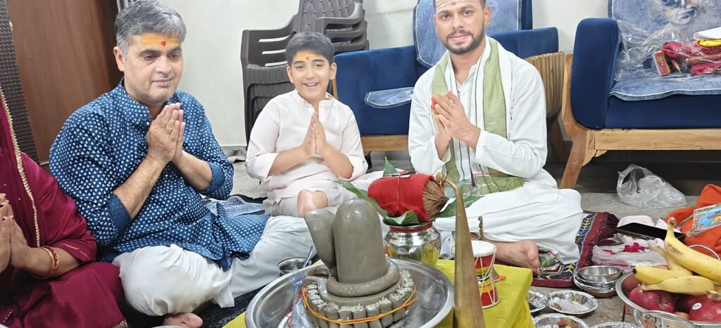A family and the Vandanam pandit with folded hands beside the Shivling during a Rudrabhishek at home in Delhi