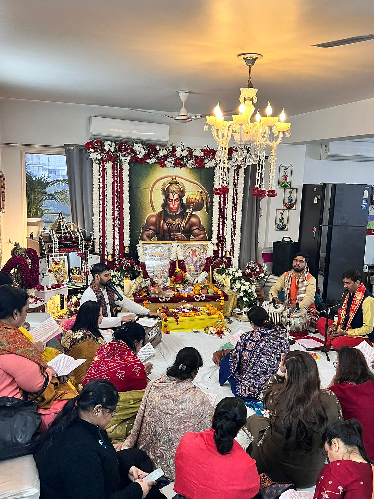 Guests following the sangeetmay Sunderkand Path in their gutkas while the mandali sings, at a home in Delhi NCR