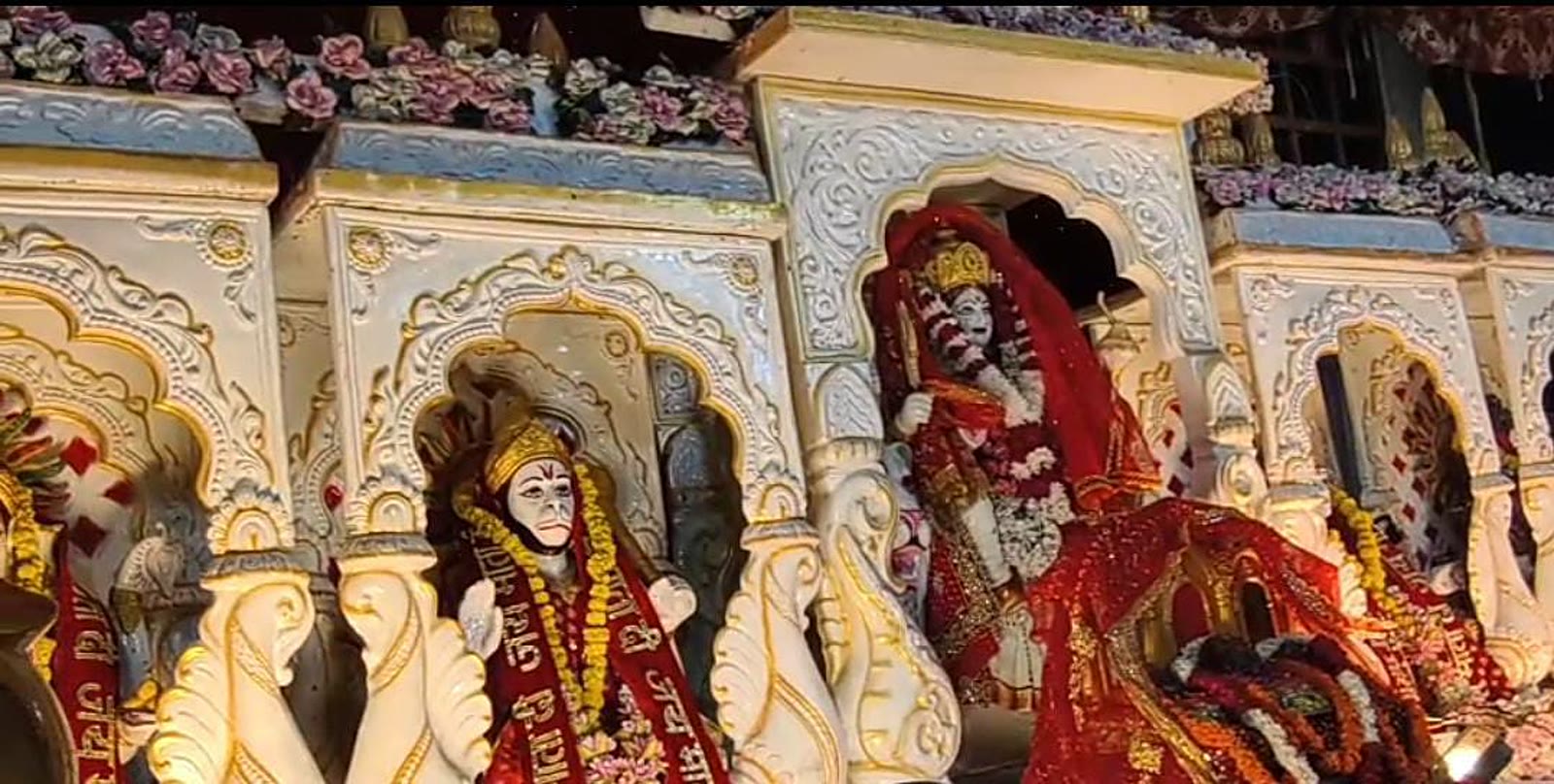 Hanuman ji and a red-draped idol set in a carved white marble jharokha style decoration