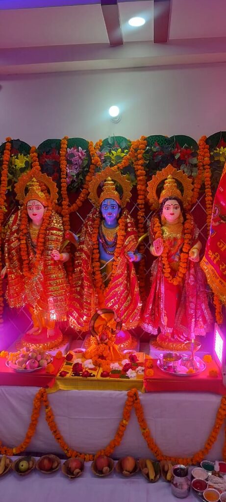 Ram, Lakshman and Sita idols in gold attire with marigold garlands and fruit offering thalis